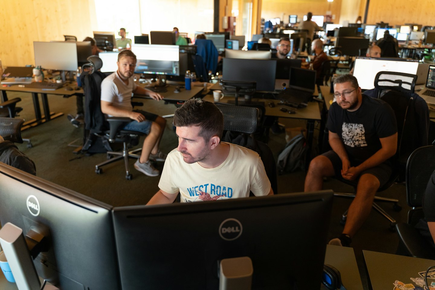 IT-spetsialistid teevad kaasaegses kontoris oma laudade taga koostööd.
